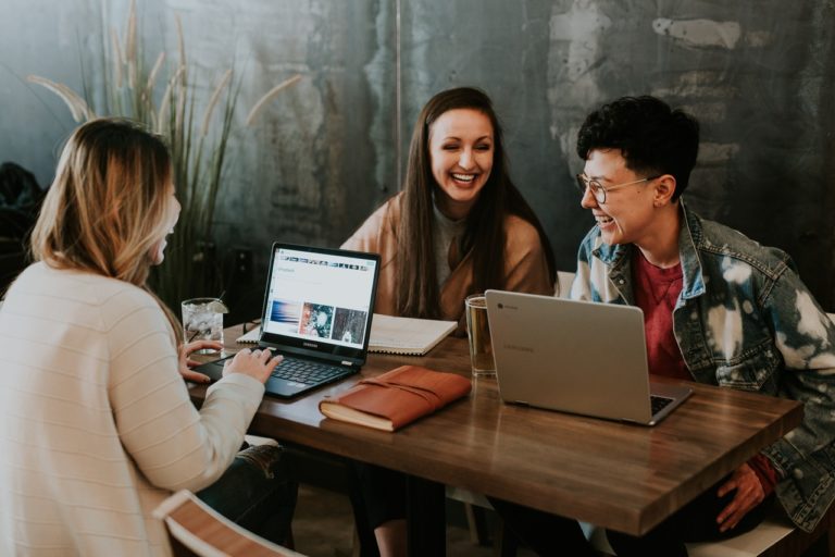 Three adults chatting and working on laptops